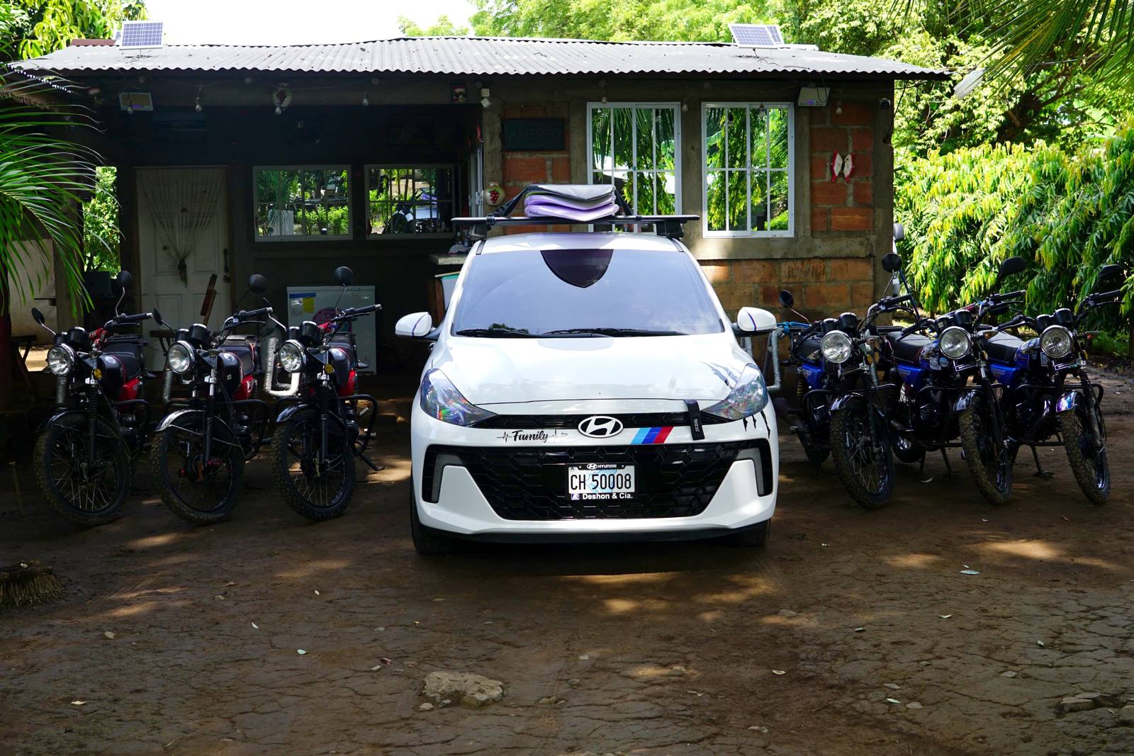 Panda on Wheels shop in Aserradores: motorcycles lined up on both sides of a white car parked in front of the house