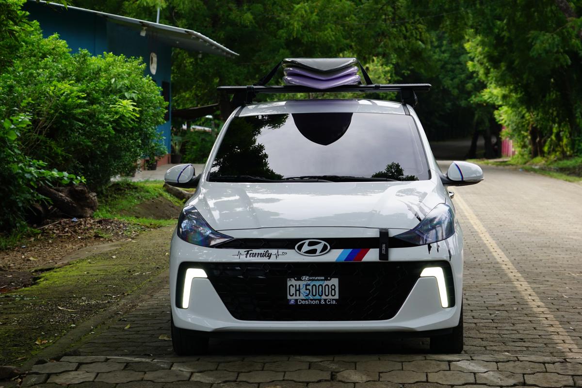 Front view of the white taxi with surfboards strapped to the roof rack