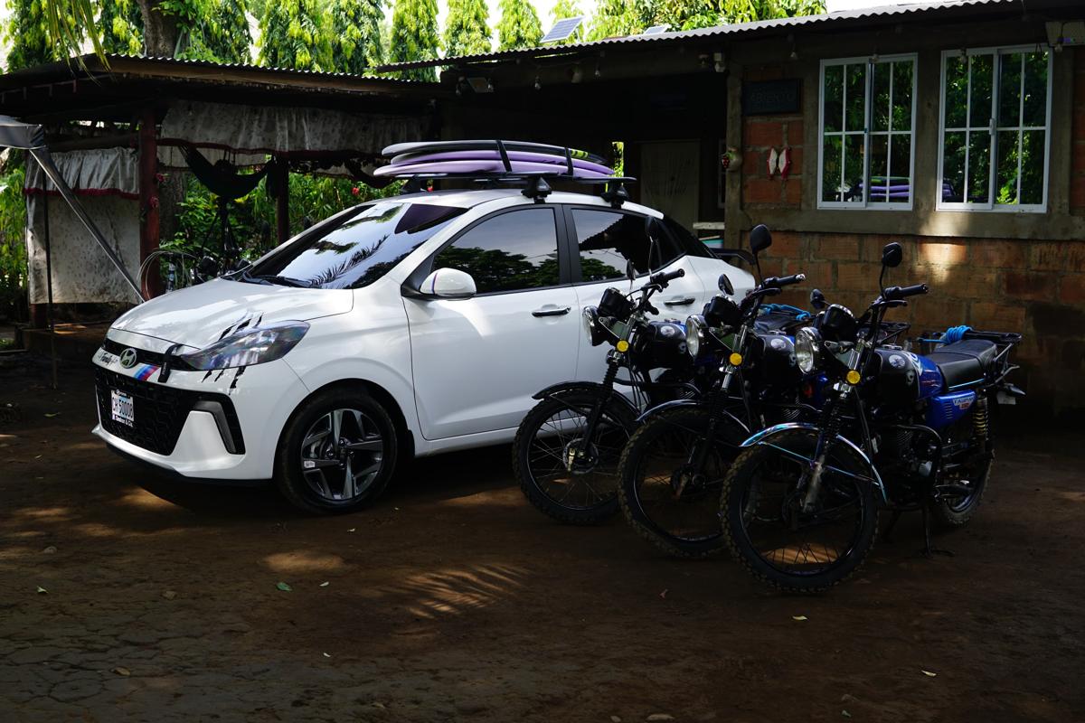 Three blue rental motorcycles parked next to the white Panda on Wheels taxi